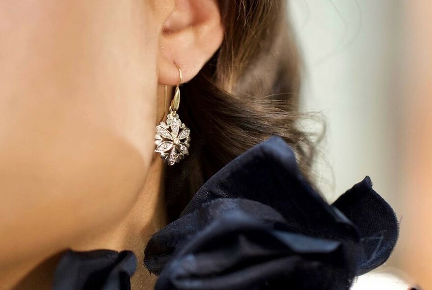 Close-up of woman wearing diamond earring.
