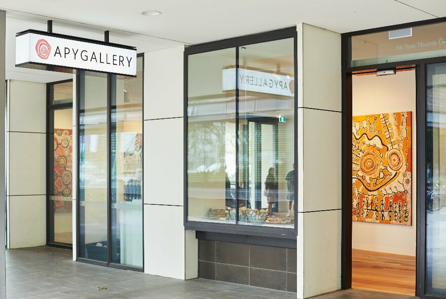 Exterior of APY Gallery with long window panes and Indigenous art visible through the open door. 