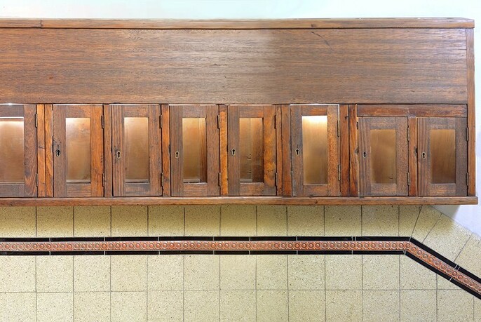 Row of wooden restored mailboxes above cream-coloured tiles with a thin row of brown striped tiles.