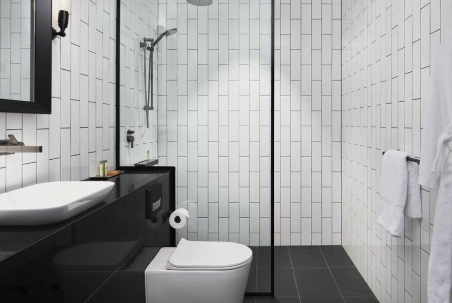 A white tiled bathroom with a black vanity and black tiled floor.