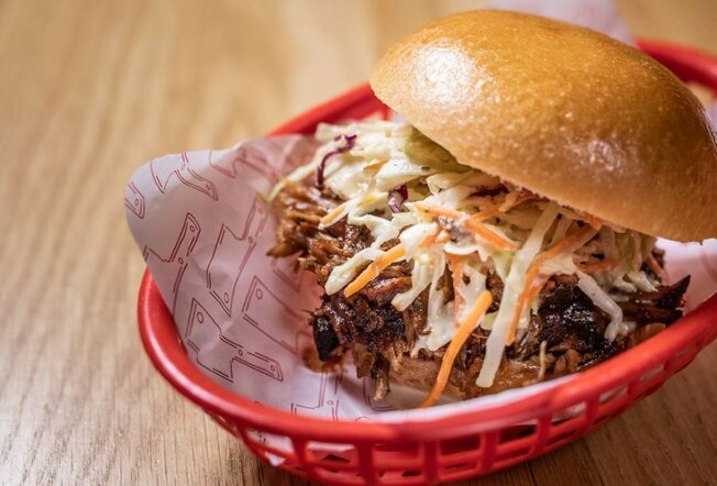 A burger with slaw in a red basket.