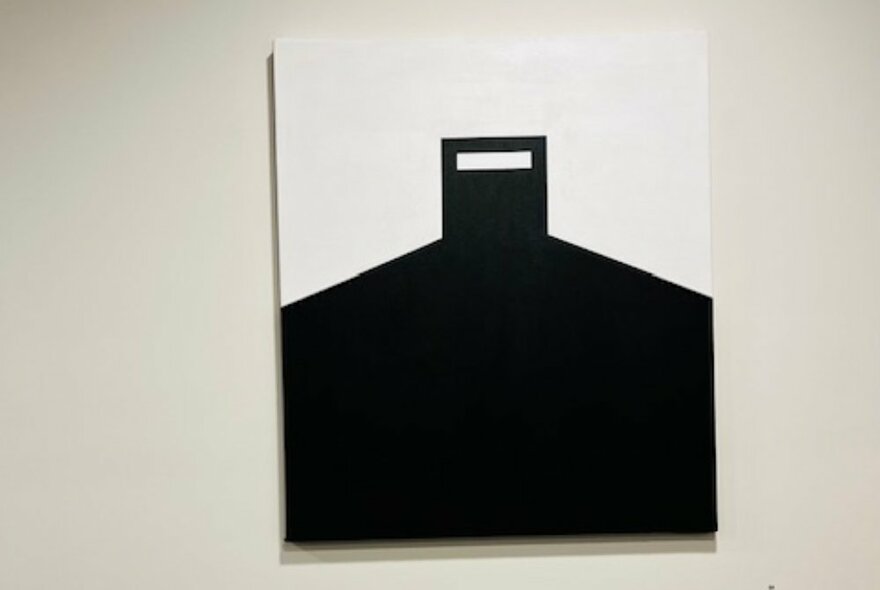 Abstract Ned Kelly painting, black armour shape against a white sky.