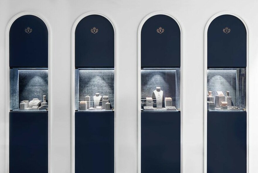 Four jewellery cabinets against dark blue background set within white arches.