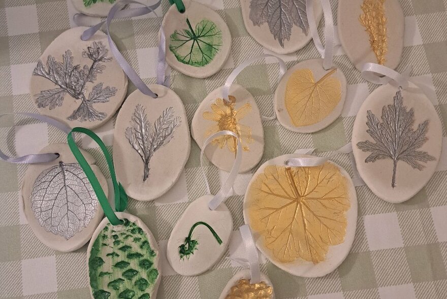 Selection of clay pendants and small wall hangings with different coloured foliage patterns on them.