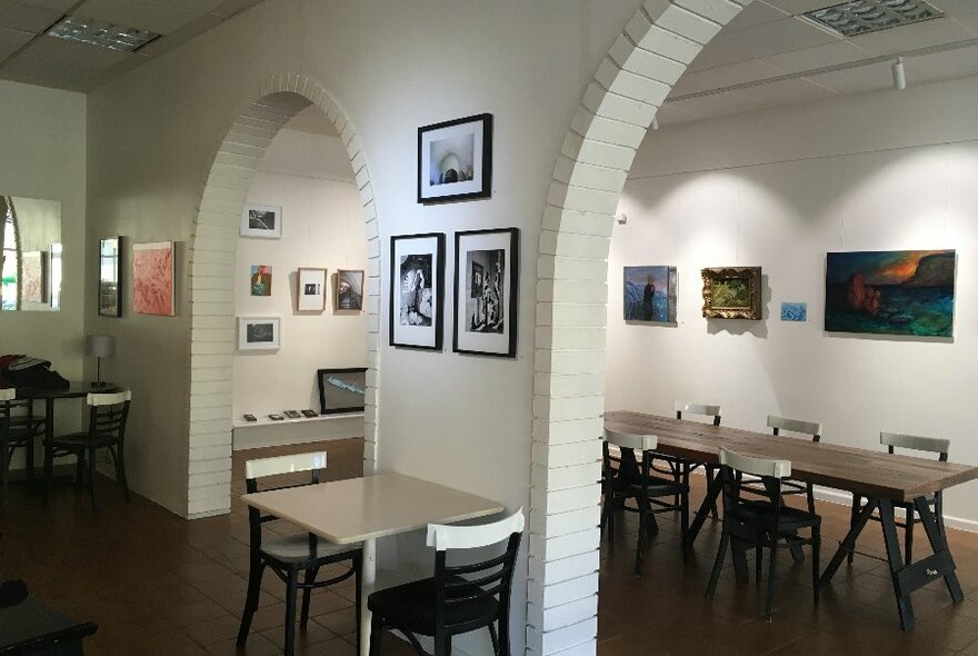 Interior of a cafe with arches and art on the walls. 