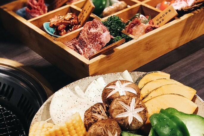 Wooden tray with dishes of condiments, plate of mushrooms and other vegetables.
