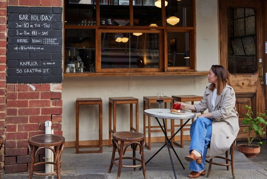 A woman drinking wine outside a bar.