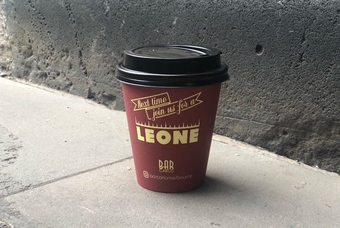 Cup of coffee in a Leone Bar takeaway cup sitting on the ground. 