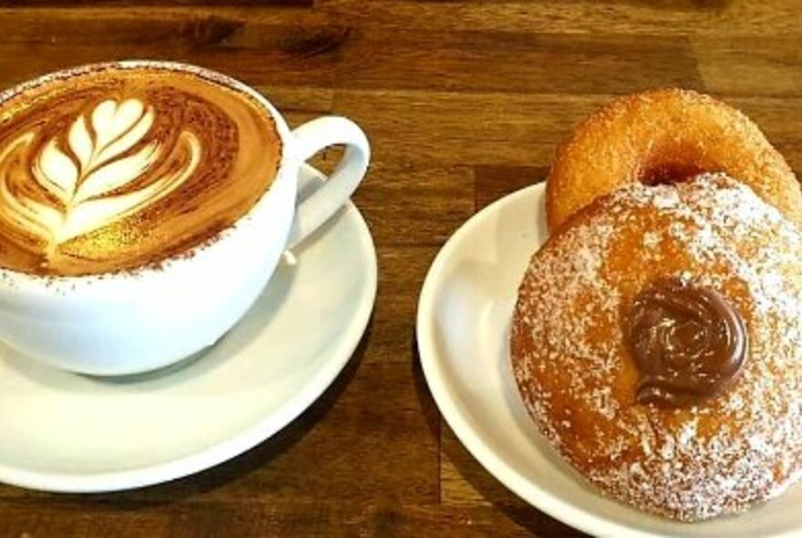 Coffee and donuts on white crockery on a wooden table.