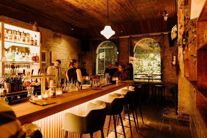 A cosy bar with comfy stools and arched windows. 