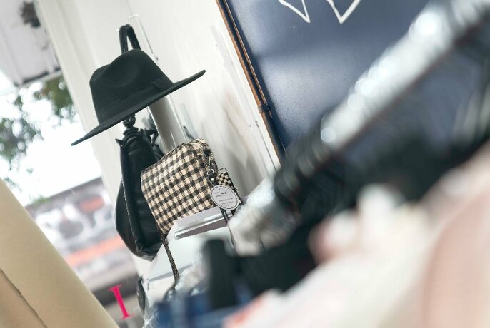 Looking through a shop at a display featuring a hat and handbag. 