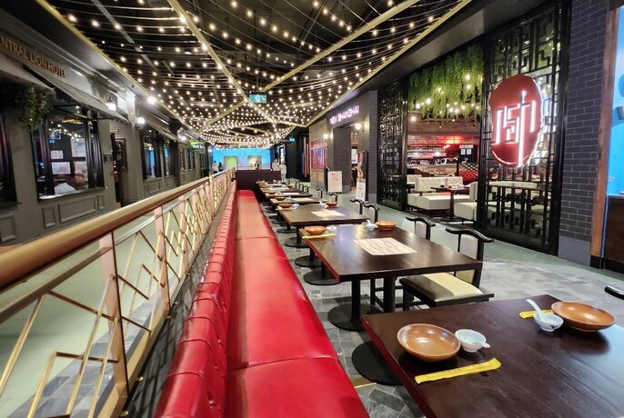 Exterior of New Shanghai restaurant in a shopping centre, showing tables and seats in the walkway in front of the restaurant.