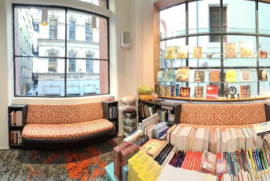 A fish eye image of the interior of the TS Bookshop, showing shelves of books and orange sofas. 