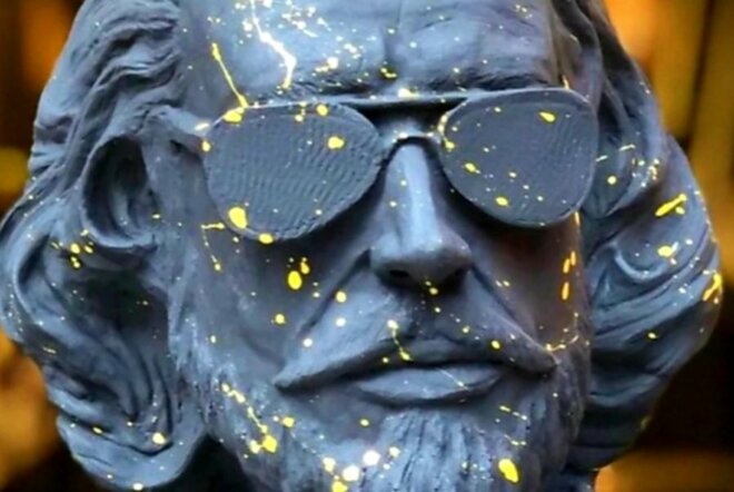 Bust of Shakespeare splattered with yellow paint and wearing sunglasses.