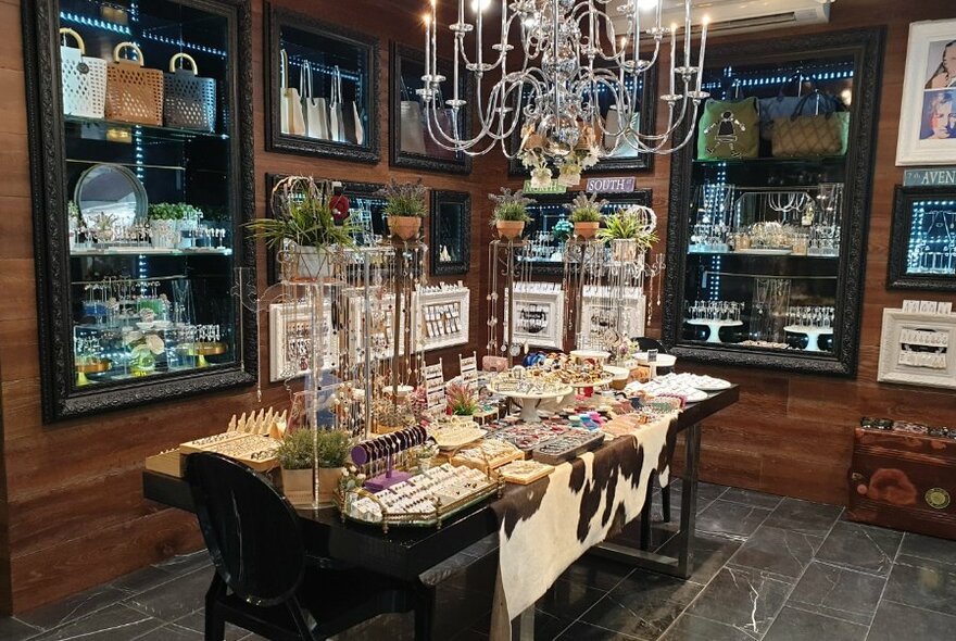 Interior of Mouche retail space with glass cabinet displays and a table featuring homewares and jewellery.