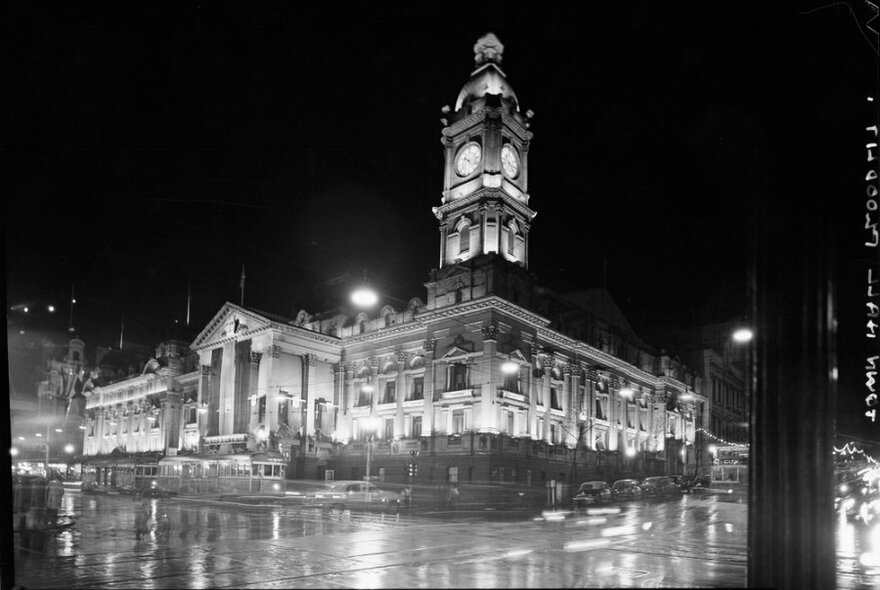An old black and white photo of Melbourne Town Hall on a rainy night.