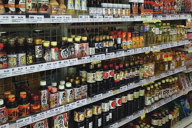 Wide range of Asian sauces and condiments lining supermarket shelves.