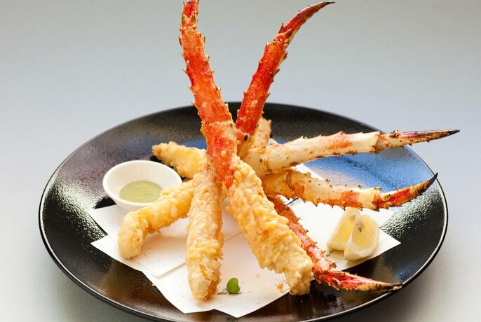 Black dish with battered crab legs and condiments.
