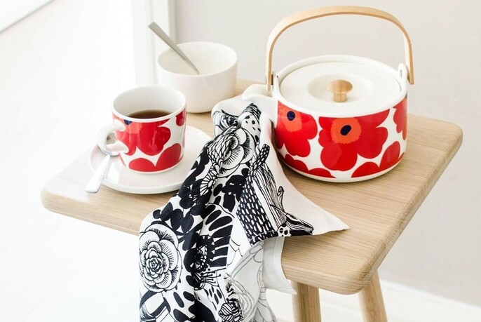 Crockery with bold, red floral motif and a tea towel with black and white pattern. 