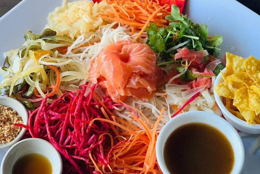 Vibrantly coloured grated Malay salad dish with carrot, beetroot, salmon and sauces.