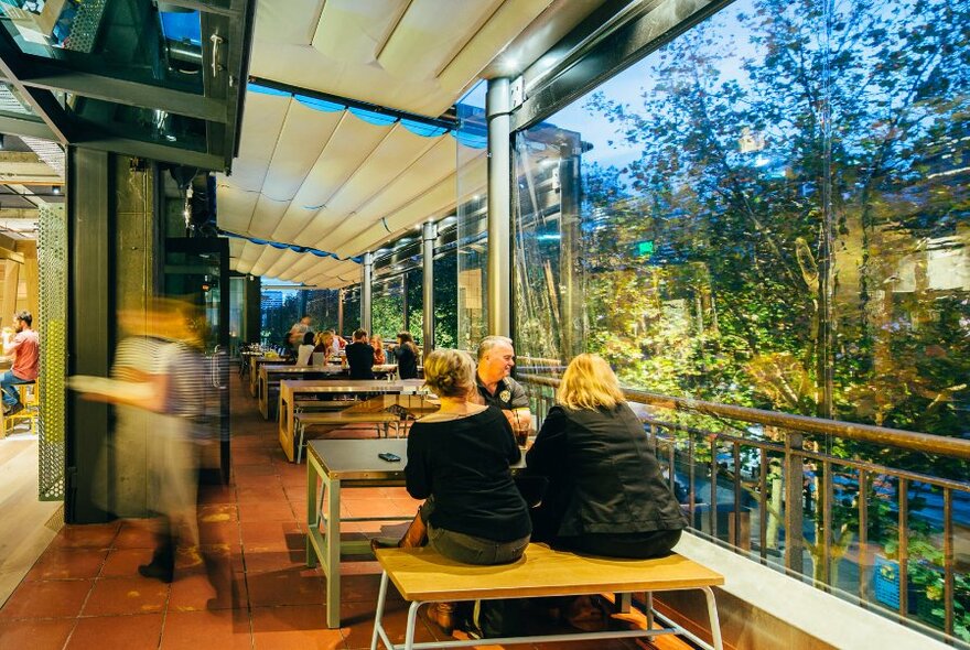 Patrons seated outdoors at Hophaus with views of the Yarra River and trees.