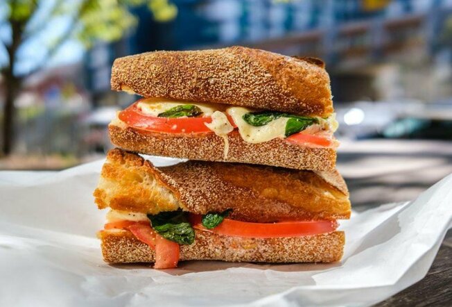 A stack of tomato and cheese sandwiches on crusty bread.
