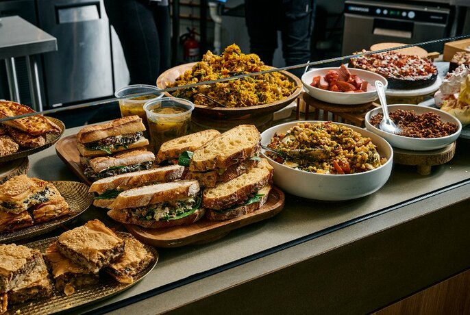 A table filled with plates of sandwiches and bowls of food. 