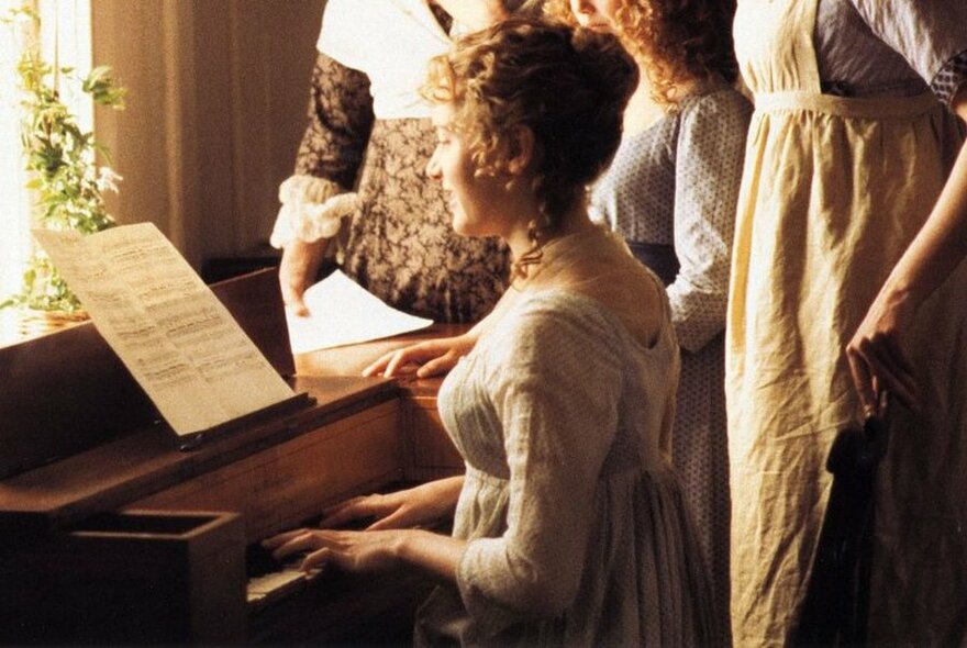 Woman in Victorian dress seated at piano, in window, surrounded by other women (visible knee to bust only).