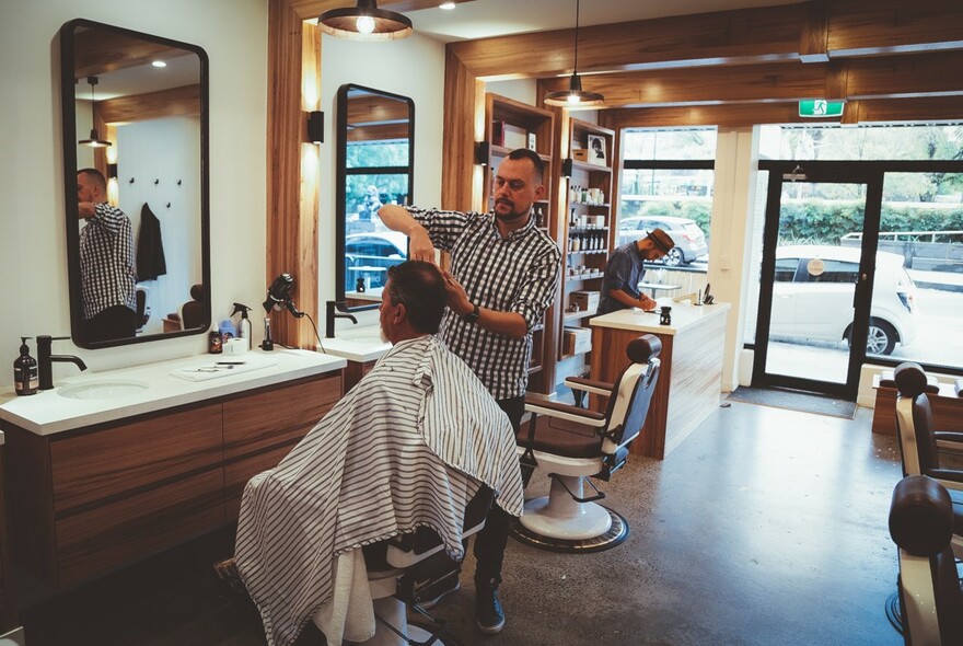 Interior of Alpha Barbers with man getting his haircut.