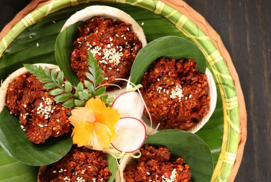 Spicy red Sichuan food in banana leaf cups.