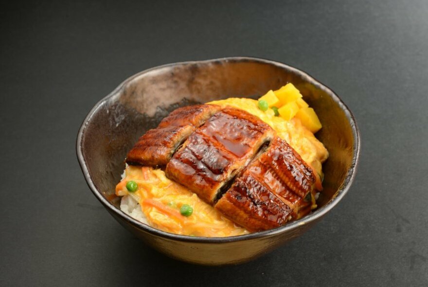 A delicious Japanese meal in a beaten silver dish, with white rice, omelette and grilled fish.