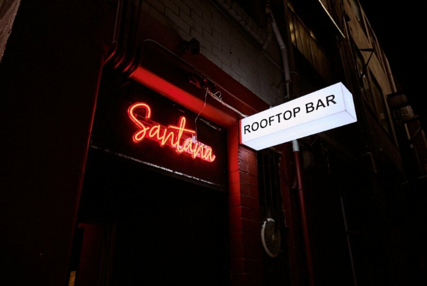Dark entrance to a bar with a neon sign.