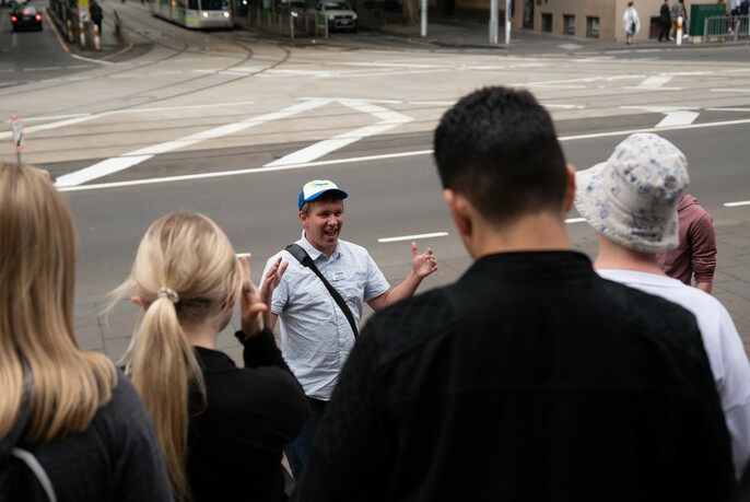 Tour guide talking with guests, on a city street. 