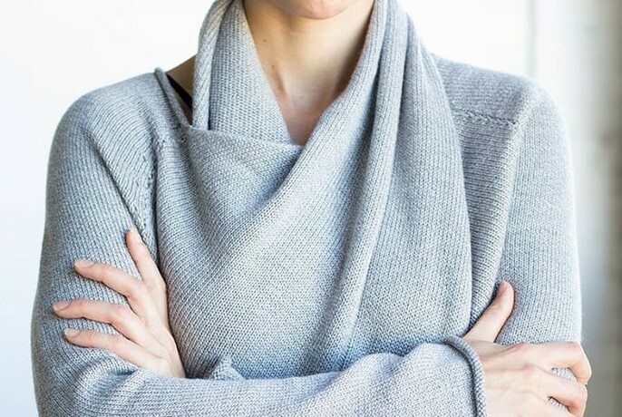 Model wearing light blue, soft woollen wrap-around jumper with arms crossed.