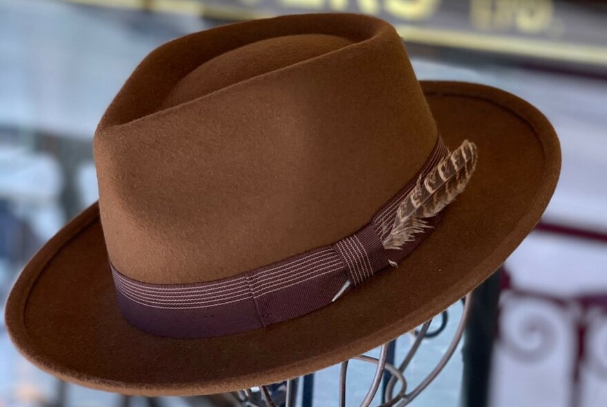 Brown Akubra-style hat with a feather in the hat band.