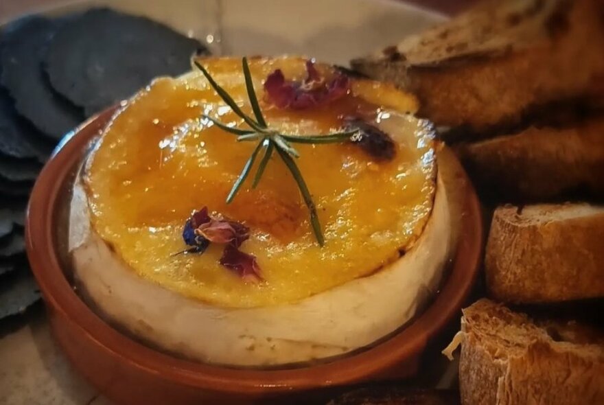 Cheese souffle in a terracotta ramekin, with slices of toasted bread alongside.