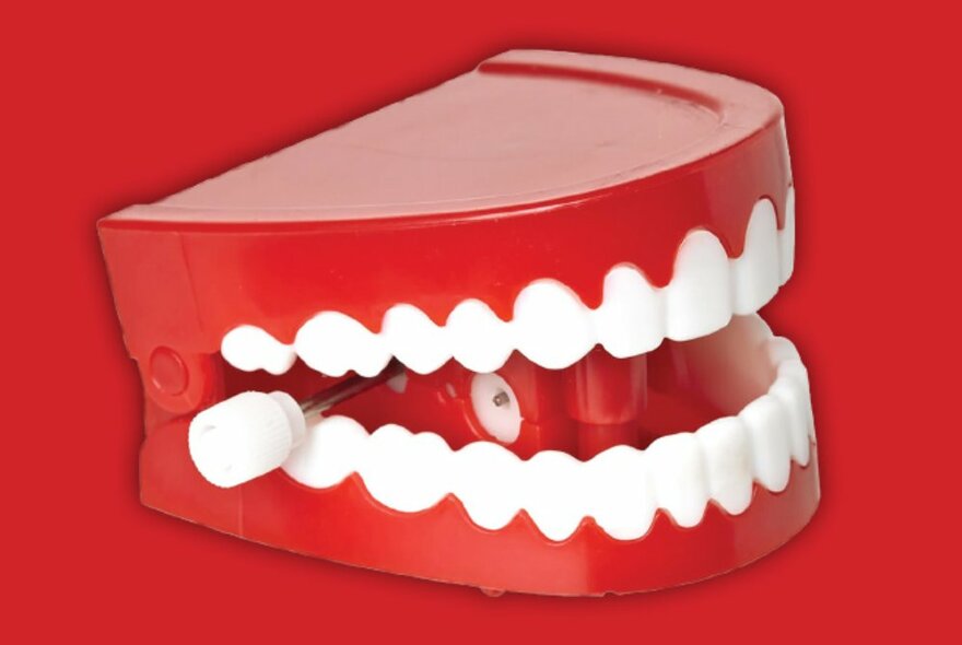 Novelty wind-up teeth against a red background.