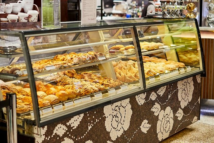 Pastries and other food in a long display cabinet inside a cafe.