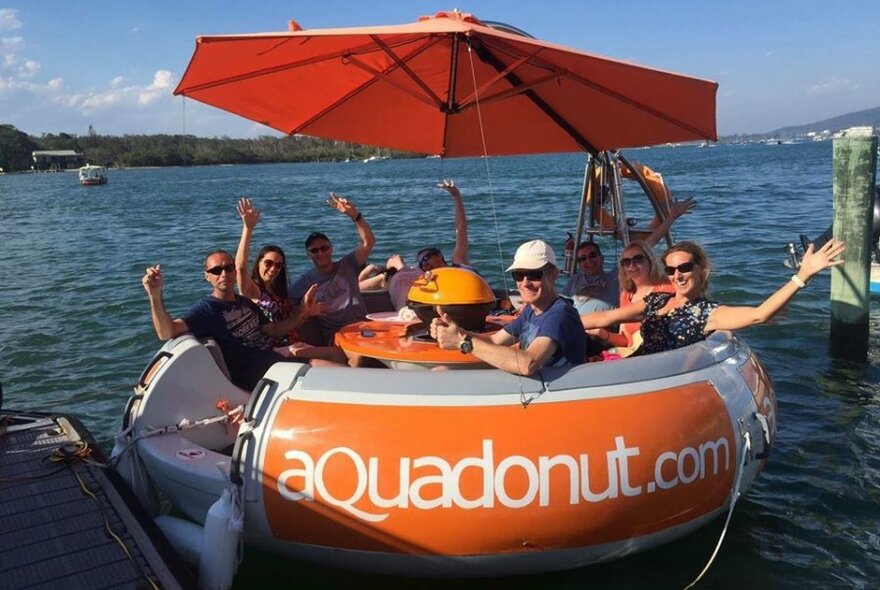 Eight excited passengers on an orange Aqua Donut boat. 