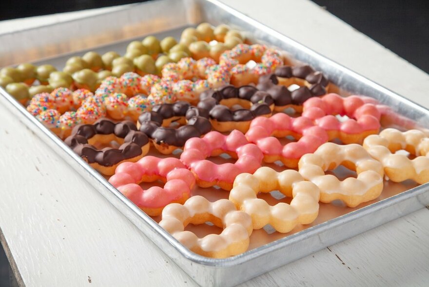 A tray of five different flavoured donuts, presented in four rings with seven balls.