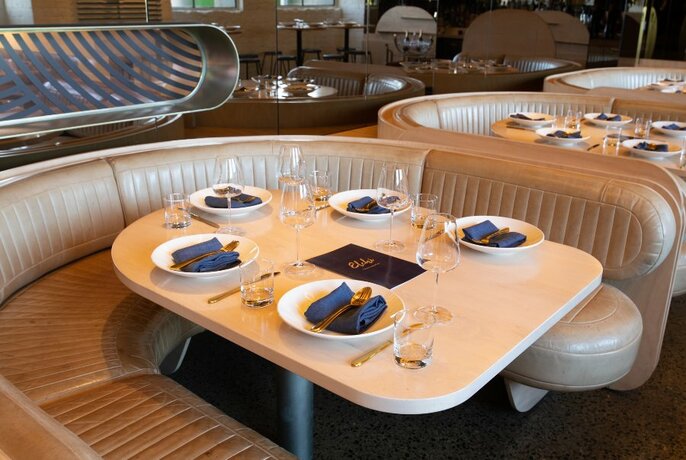 Semi-circular banquettes and a table set for service in the interior of Elchi restaurant.