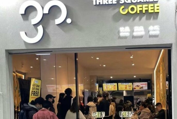 People queuing to enter Three Square Coffee cafe filled with people.