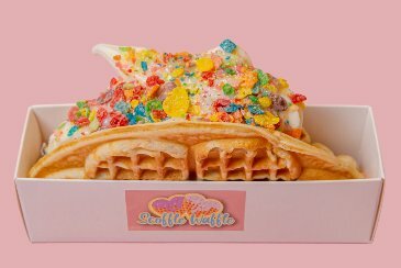 Waffle with colourful sprinkles, upright, in small white box.