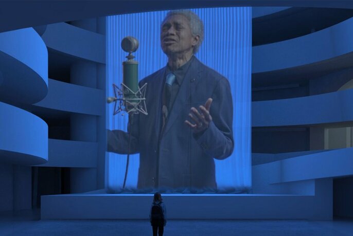 Image of a person with their eyes closed, wearing a suit jacket and tie, singing into a microphone, projected onto a large silk screen that hangs in the foyer of an open airy space; at the bottom of the frame a person is looking up at the projection.