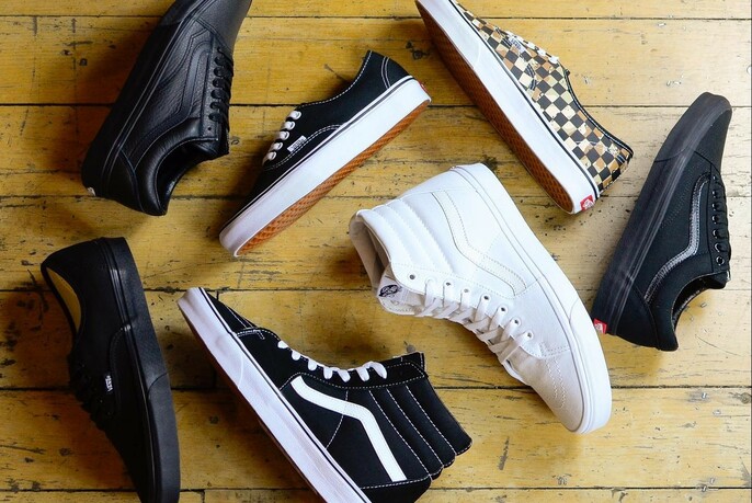 Black and white sneakers on a wooden floor.