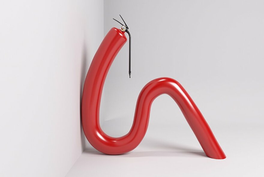 A red curved piece of metal and plastic resting against a white wall.