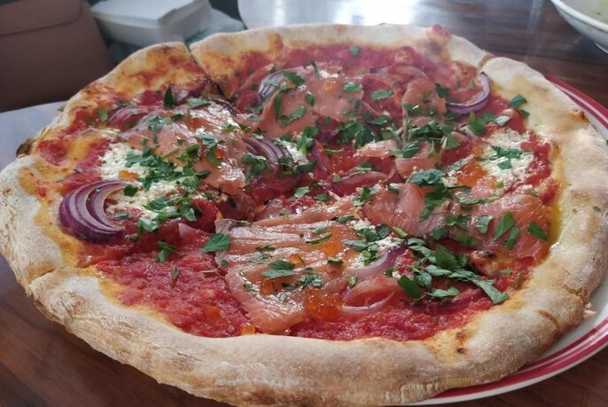 Close up of a rustic pizza with onions and herbs.
