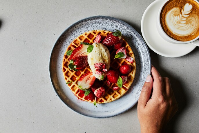 Waffle with strawberries and a cup of coffee.