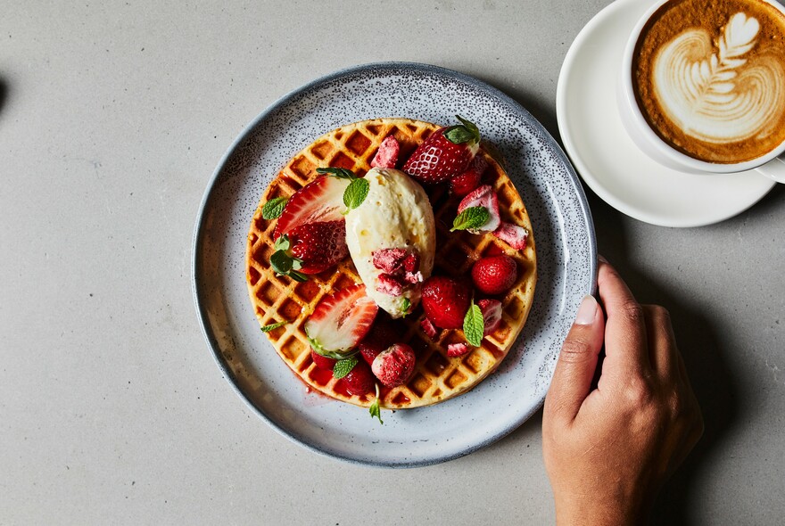 Waffle with strawberries and a cup of coffee.