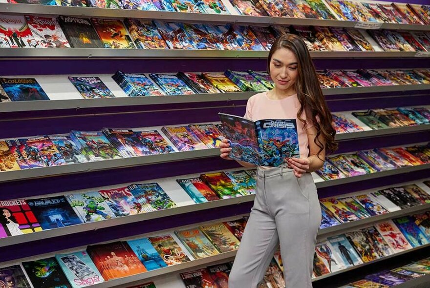 A woman reading comic books in a store.